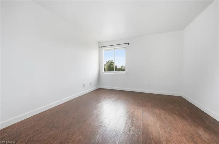 Spare room with baseboards and dark wood-type flooring