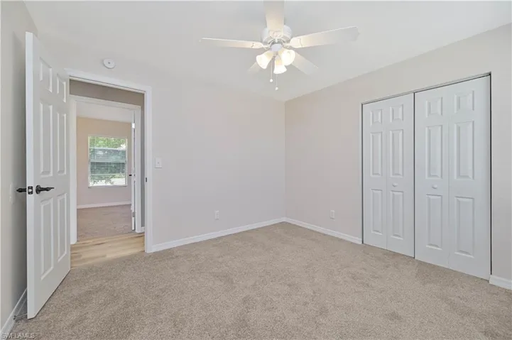 Neutral-toned carpeted interior space with a ceiling fan with integrated lighting