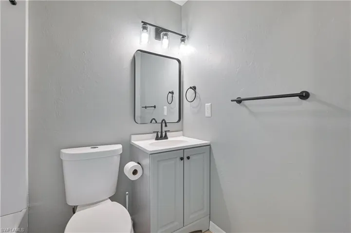 Contemporary vanity with a white countertop, matte black hardware, and an illuminated mirror