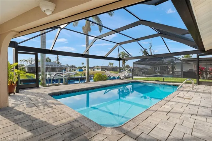 Swimming pool with a patio area, a boat dock, a water view, and a lanai