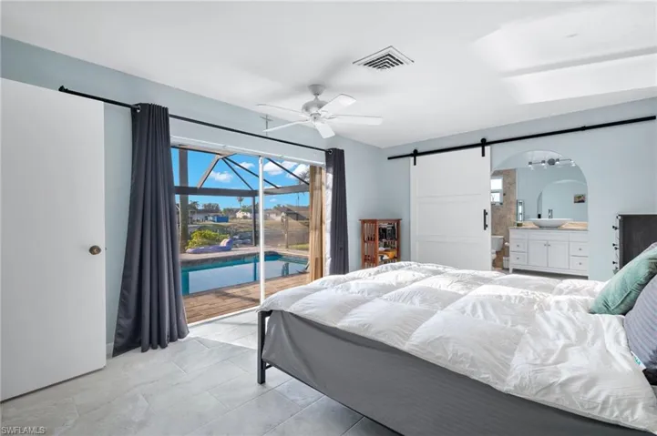 Bedroom featuring access to exterior, a barn door, arched walkways, a sunroom, and ceiling fan