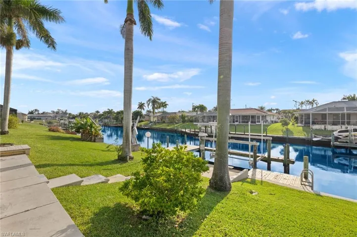 Dock featuring a water view, boat lift, a yard, and a residential view