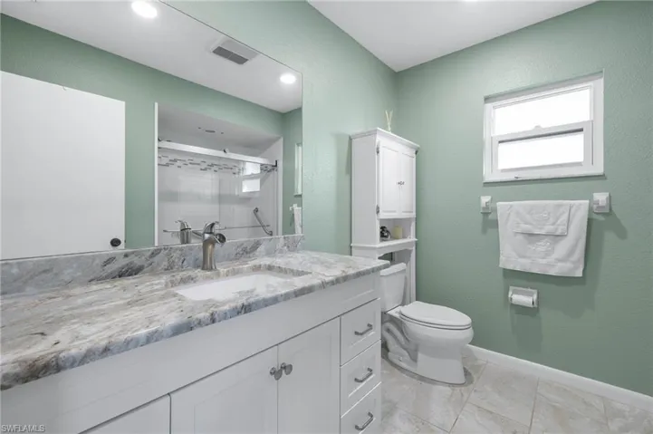 Full bathroom with vanity, a shower stall, and a textured wall