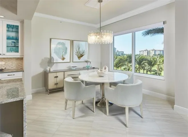 Dining space with ornamental molding, a chandelier, and light tile patterned flooring