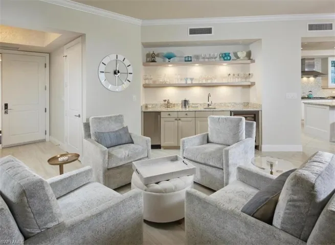 Living room featuring ornamental molding, bar with sink, and beverage cooler