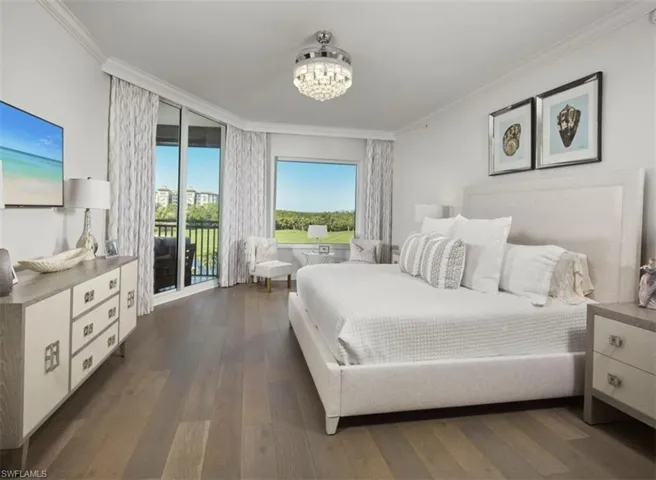 Bedroom with ornamental molding, dark wood-type flooring, access to outside, and a chandelier