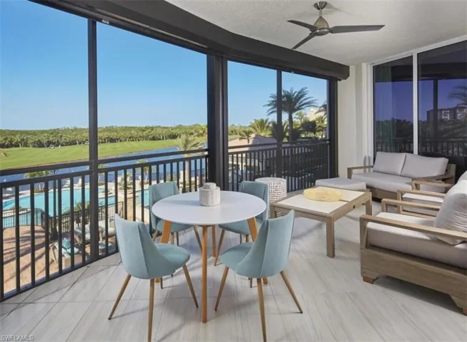 Sunroom featuring a wall of windows, a textured ceiling, view of golf course, and a water view