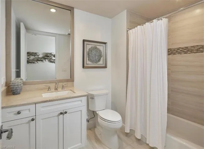 Bathroom featuring vanity, shower / tub combo, and recessed lighting