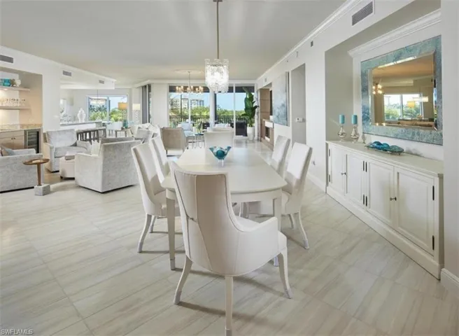 Dining space with ornamental molding, a chandelier, beverage cooler, and floor to ceiling windows