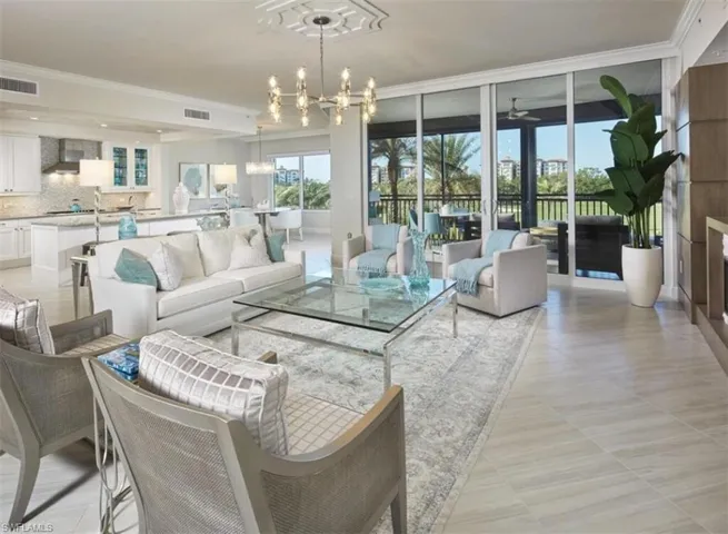 Living area featuring a chandelier, plenty of natural light, expansive windows, ornamental molding, and a ceiling fan