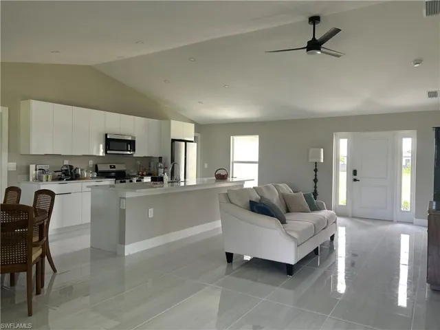 Open-concept living space featuring a vaulted ceiling and light-toned tile flooring