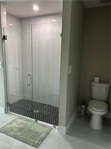 Spacious shower with clear glass enclosure and black hexagonal tile flooring