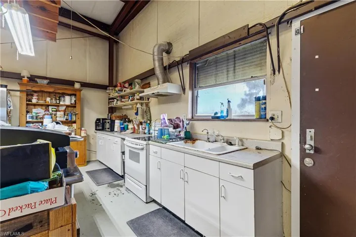 Kitchen with sink, electric stove, and white cabinetry
