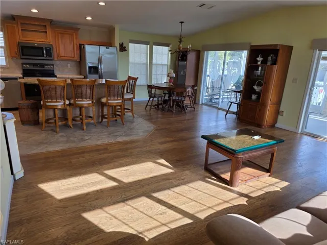 Living area with light wood-style floors, vaulted ceiling, and a chandelier