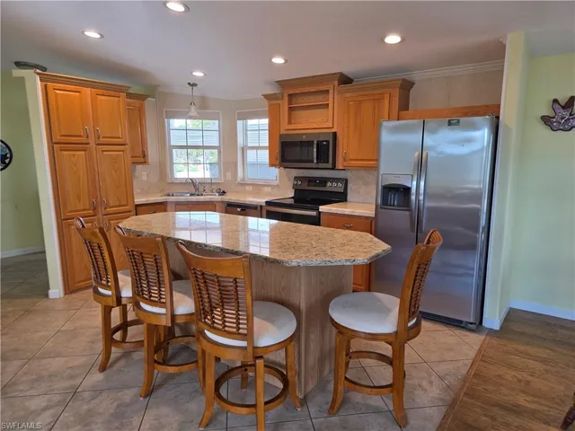 Kitchen featuring stainless steel appliances, a breakfast bar area, light stone countertops, tasteful backsplash, and a center island