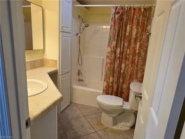 Full bath featuring vanity, shower / bath combo, and light tile patterned floors