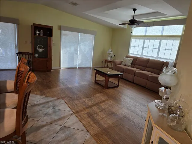 Living room featuring a raised ceiling, a ceiling fan, and tile patterned floors