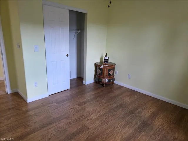 Unfurnished bedroom featuring dark wood finished floors and a closet