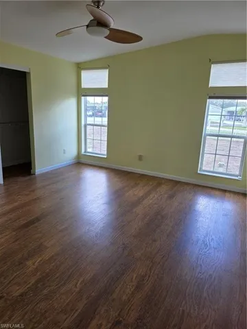 Spare room with dark wood finished floors, ceiling fan, and lofted ceiling