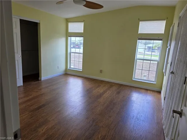 Unfurnished room featuring vaulted ceiling, healthy amount of natural light, dark wood finished floors, and a ceiling fan