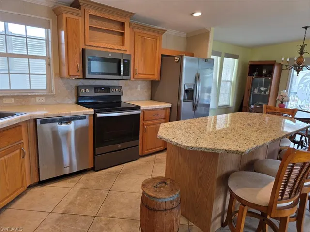 Kitchen with stainless steel appliances, healthy amount of natural light, tasteful backsplash, and a kitchen breakfast bar