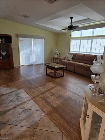 Living area with a tray ceiling, ceiling fan, and tile patterned floors