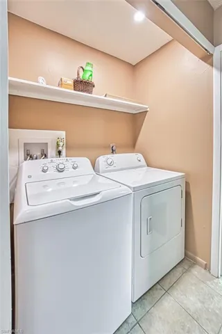 Washroom featuring washing machine and clothes dryer and light tile patterned flooring