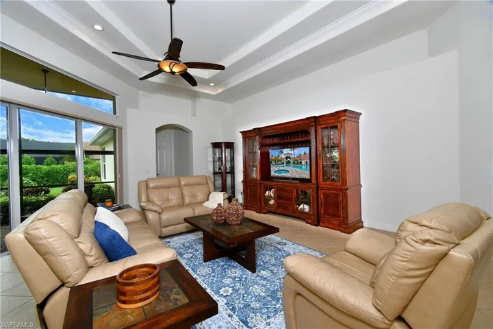 Living room featuring light tile patterned floors, arched walkways, a ceiling fan, recessed lighting, and ornamental molding