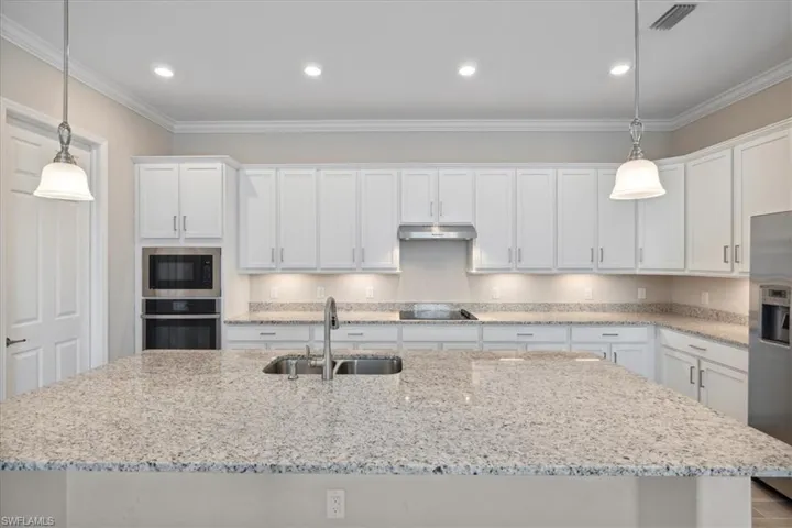 Kitchen featuring sink, crown molding, stainless steel appliances, and a center island with sink