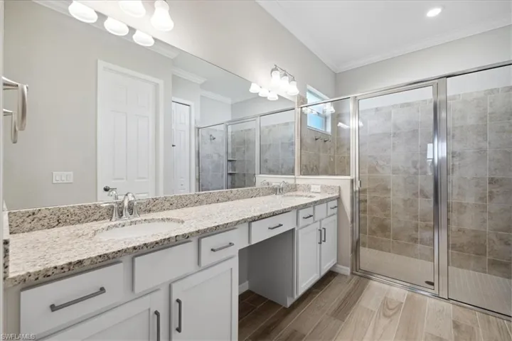 Bathroom featuring walk in shower, crown molding, and dual bowl vanity