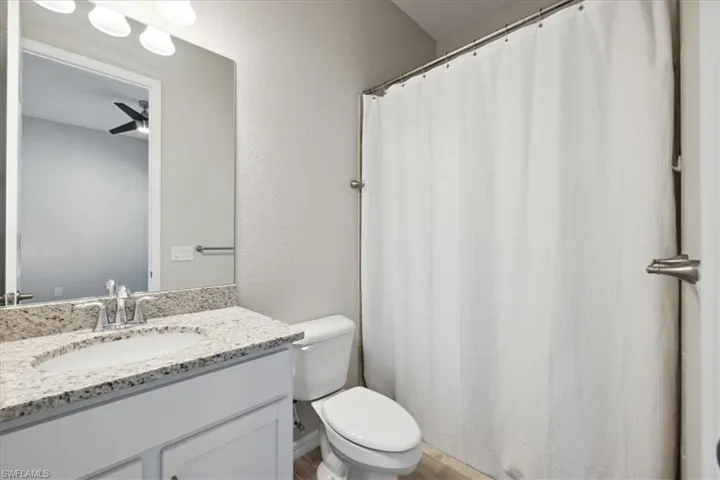 Ensuite bath featuring vanity, ceiling fan, and toilet