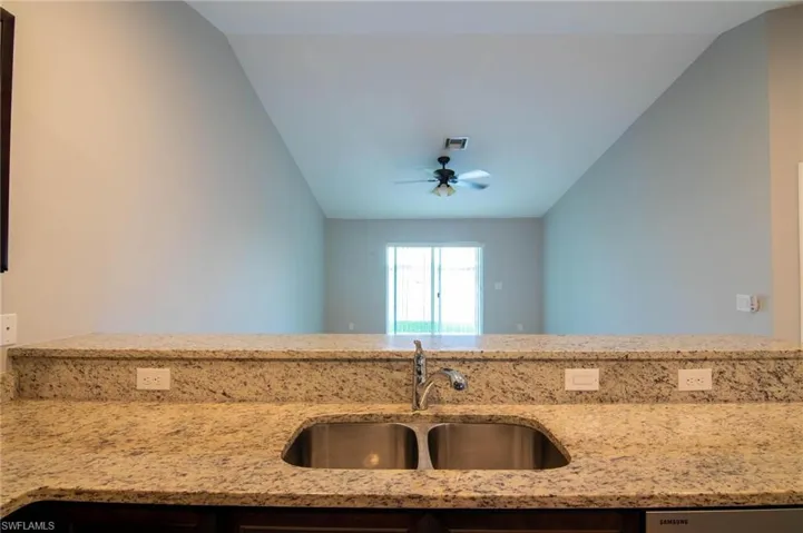 Kitchen featuring light stone countertops, lofted ceiling, and ceiling fan