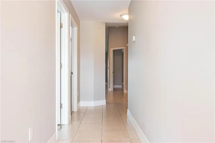 Corridor with baseboards and light tile patterned floors