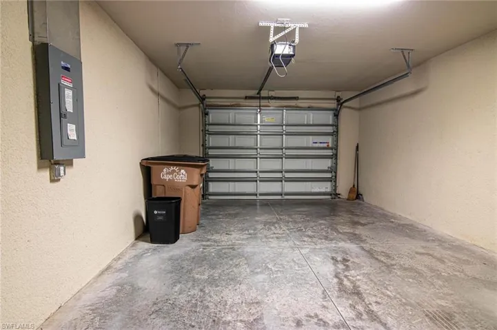 Garage featuring a textured wall, electric panel, and a garage door opener