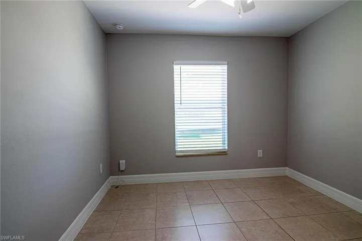 Unfurnished room featuring light tile patterned flooring and a ceiling fan