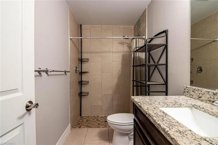 Full bathroom with vanity, tiled shower, and light tile patterned flooring