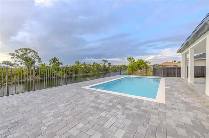 View of swimming pool with a patio, a fenced in pool, a water view, and a fenced backyard