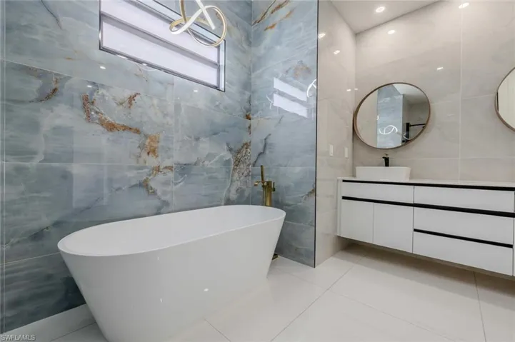 Full bathroom featuring tile walls, a soaking tub, tile patterned flooring, and vanity