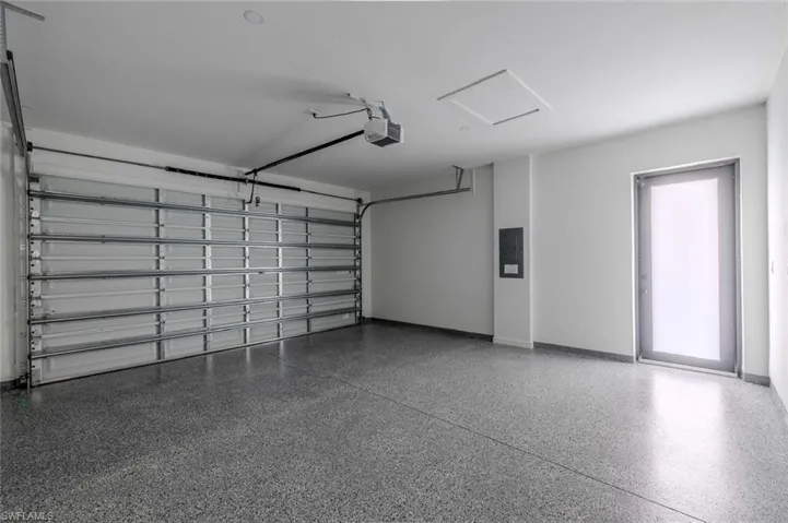Garage with baseboards, a garage door opener, and electric panel