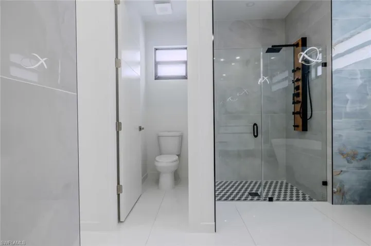 Bathroom with tile patterned flooring, toilet, and a shower stall
