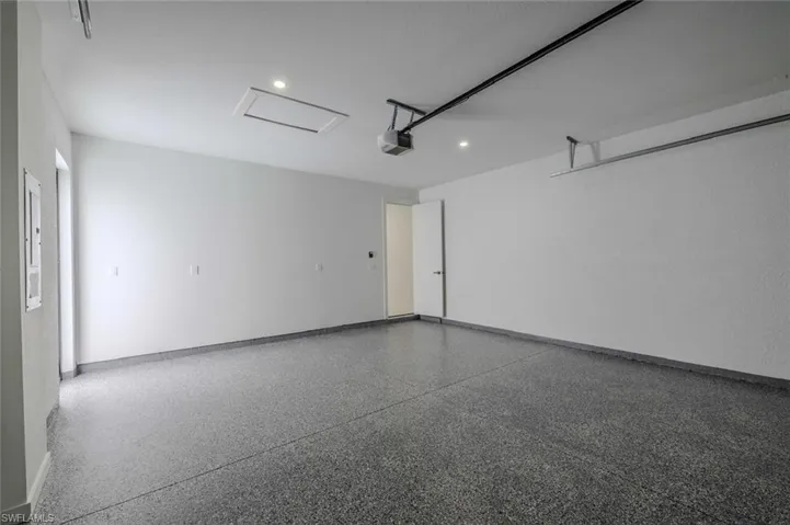 Garage with baseboards, a garage door opener, and recessed lighting