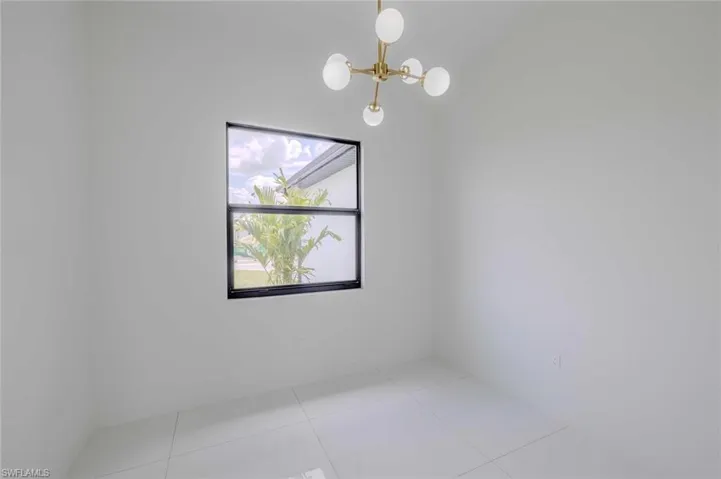 Tiled spare room with an inviting chandelier