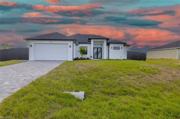 Prairie-style house featuring fence, an attached garage, stucco siding, decorative driveway, and a lawn