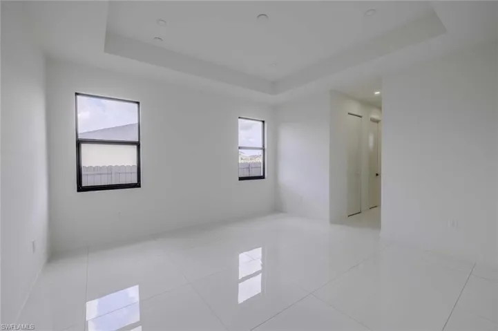 Empty room featuring light tile patterned floors and a raised ceiling