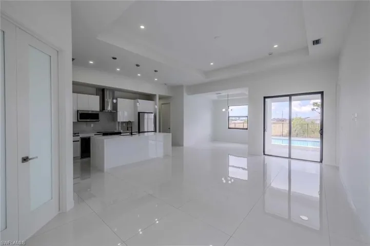 Unfurnished living room featuring light tile patterned flooring, visible vents, a sink, and a raised ceiling