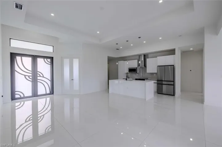 Unfurnished living room featuring visible vents, recessed lighting, a raised ceiling, a sink, and light tile patterned floors