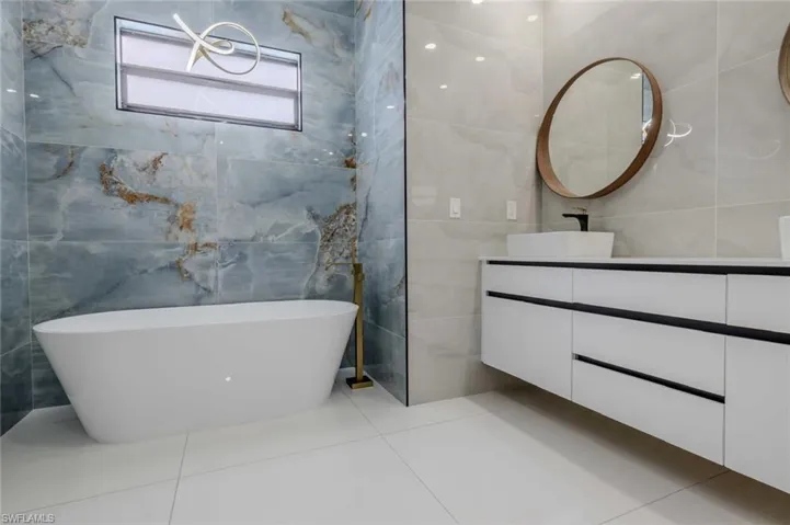 Bathroom featuring tile walls, a soaking tub, vanity, and tile patterned floors