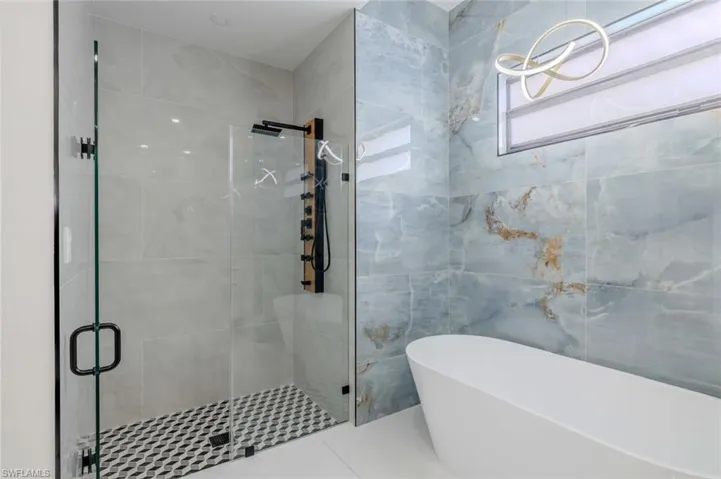 Full bathroom featuring tile walls, a freestanding bath, and a shower stall