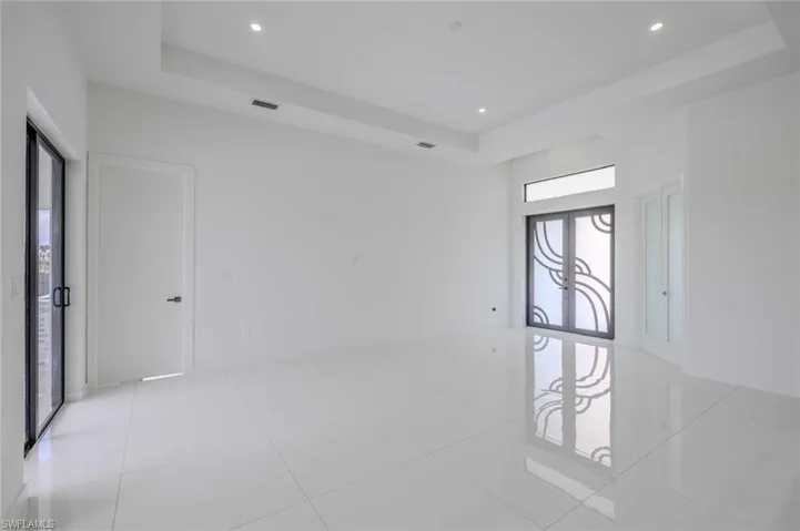 Empty room with light tile patterned flooring, a tray ceiling, visible vents, and recessed lighting