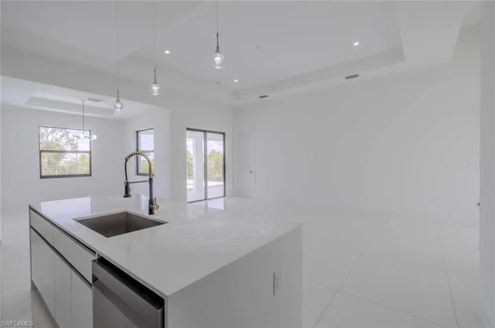 Kitchen featuring modern cabinets, dishwasher, a sink, open floor plan, and a tray ceiling